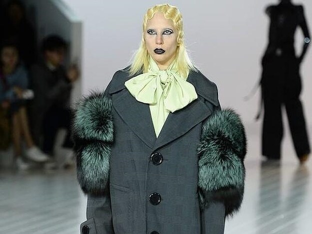 Lady Gaga con un abrigo 'oversize' sobre blusa con un lazo enorme en el cuello.