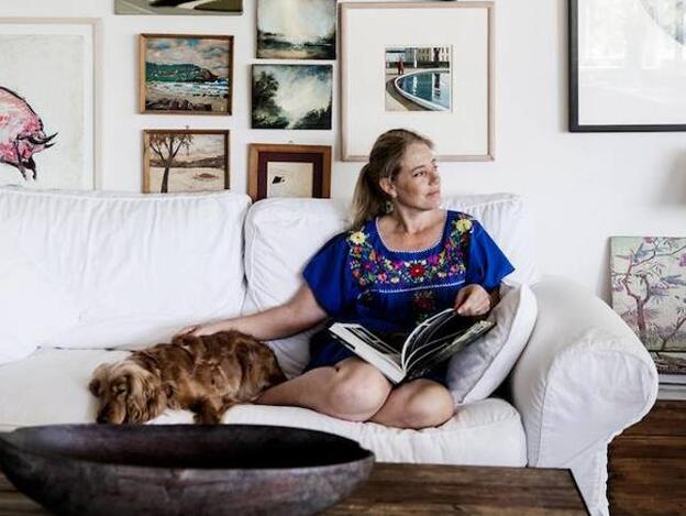 Mujerr relajada leyendo, acompañada de su perro en casa/CORDON