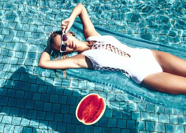 Una mujer disfrutando de una piscina sobre una colchoneta./Fotolia