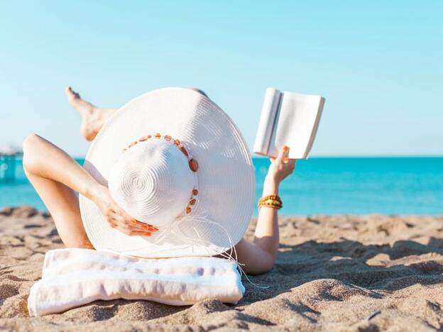 Mujer leyendo en la playa/Fotolia