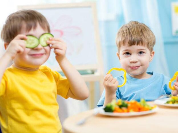 Dos niños comiendo verduras./adobe stock