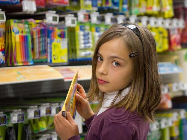 Una niña comprando material escolar./adobe stock