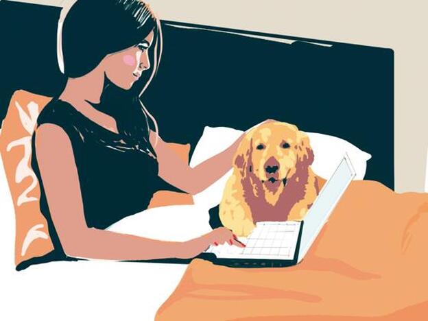 Chica con el ordenador junto a su perro en la cama./Maite niebla
