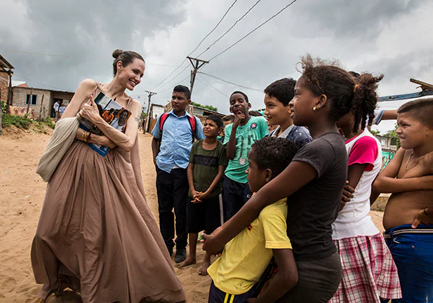 RIOHACHA, COLOMBIA - JUNE 07: (EDITORIAL USE ONLY) In this handout image provided by United Nations High Commission for Refugees, UNHCR Special Envoy Angelina Jolie speaks with children in Riohacha, Colombia, on June 7, 2019. Jolie visited the children, who had fled Venezuela, in Brisas del Norte, an informal settlement inhabited by Colombian refugees who have returned to their country as well as Venezuelans escaping a political and economic crisis back home. Over 4 million Venezuelans are now living in exile, with Colombia taking in the greatest share, even as it seeks to implement a peace deal ending five decades of conflict inside its own borders.  (Photo by Andrew McConnell / UNHCR via Getty Images)/