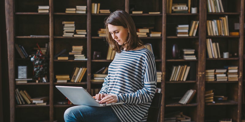 Young woman using laptop in the library/