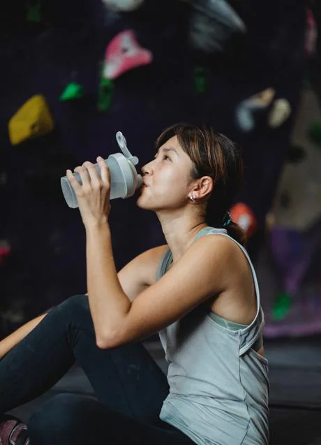 mujer joven fitness en ropa deportiva bebiendo agua después de