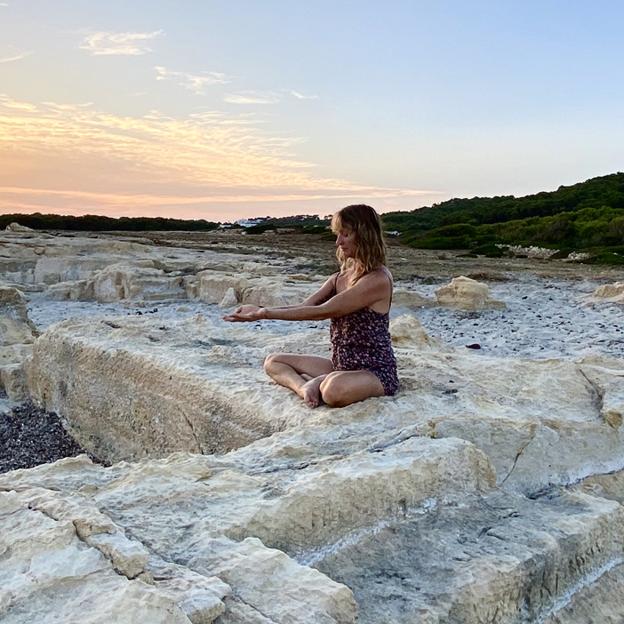 Mujer practicando yoga en una playa de Menorca. 