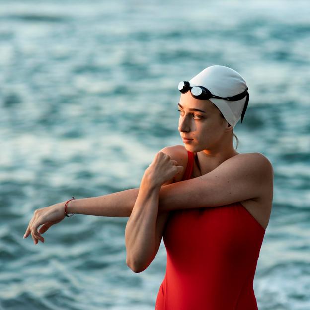 Mujer estirando antes de practicar natación. 