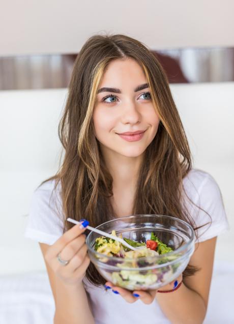 Mujer tomando una ensalada. / Imagen de diana.grytsku en Freepik.