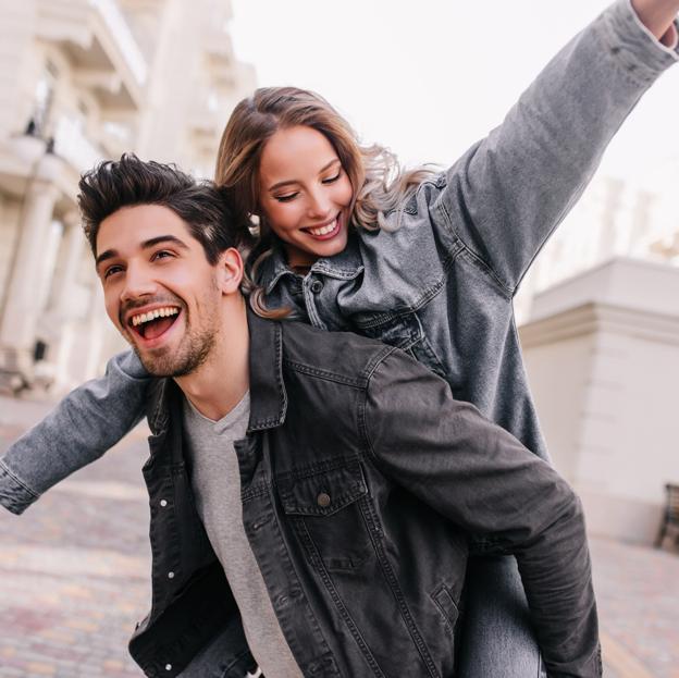 Mujer sonriente subida a la espalda de un hombre.