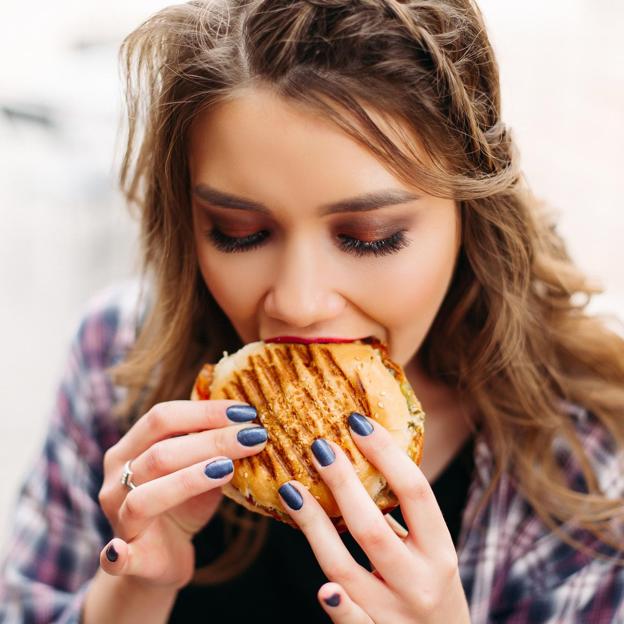 Mujer comiendo una hamburguesa. 