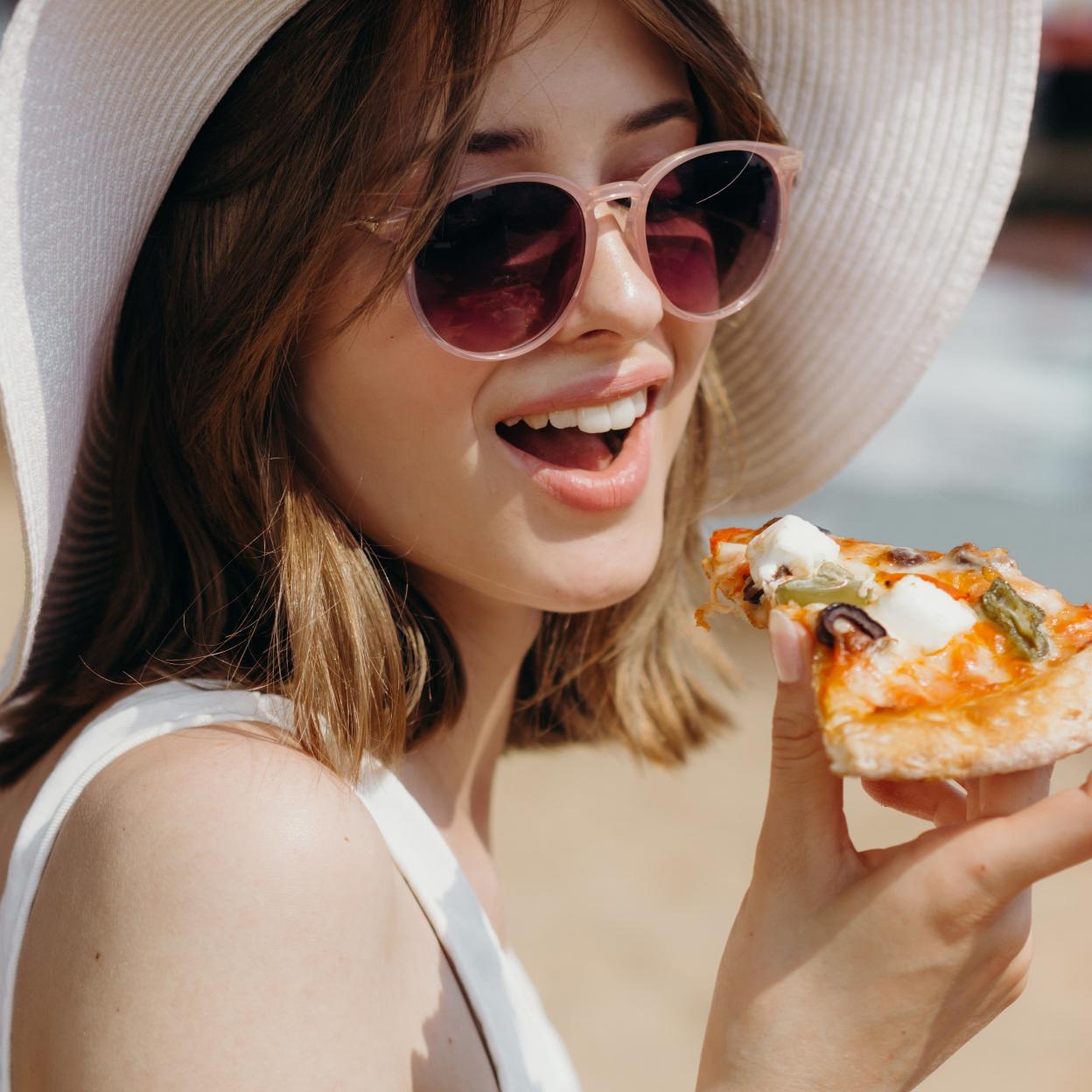 Mujer comiendo pizza/pexels