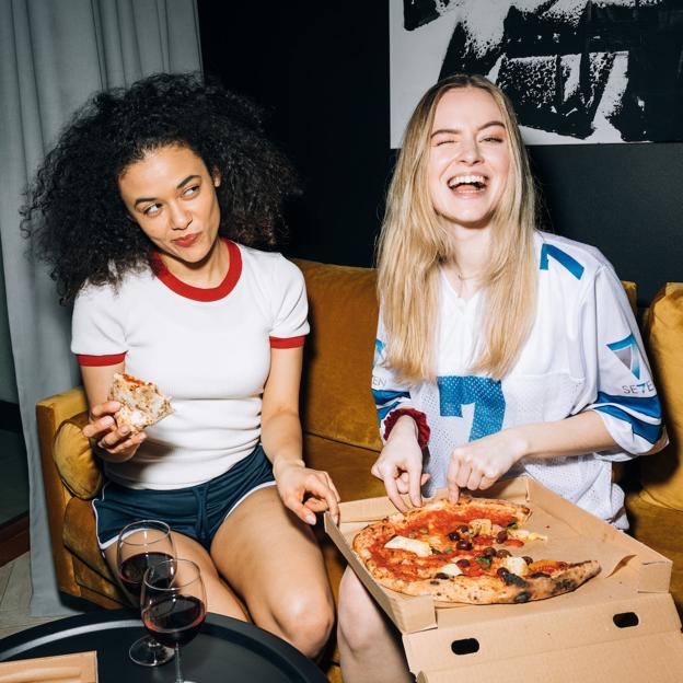 Dos mujeres comiendo pizza. 