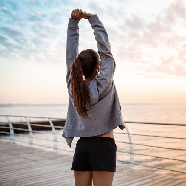 Mujer estirando frente al mar después de un entrenamiento. 