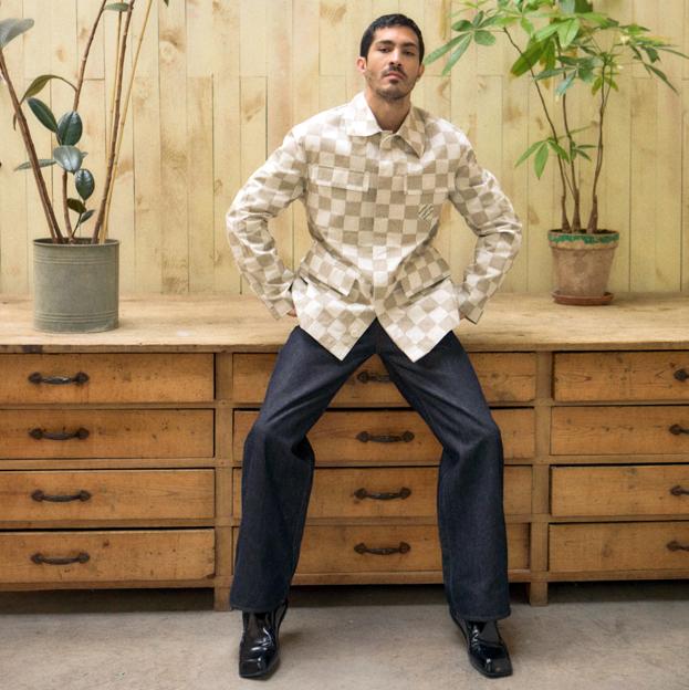 Chino Darín viste chaqueta con estampado damero de Louis Vuitton, vaqueros de Loewe y zapatos de Prada.