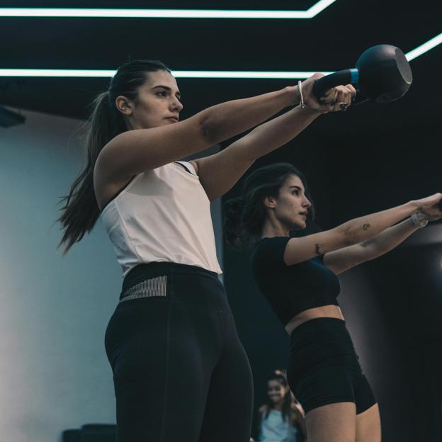 Dos chicas entrenando con pesas rusas