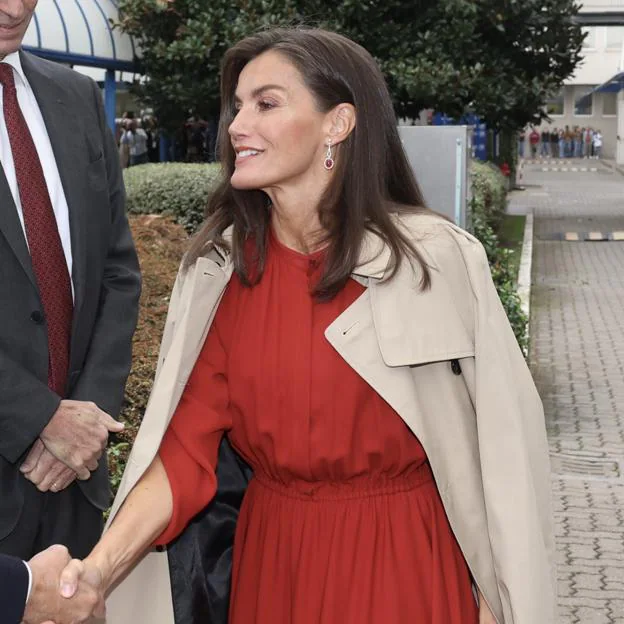 La reina Letizia viaja a Milán con un vestido rojo y gabardina para presidir el acto central del Día Mundial de la Investigación en Cáncer