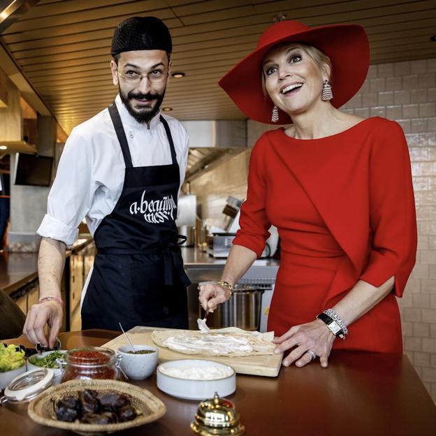 La reina Máxima, de rojo y con sombrero en un restaurante.