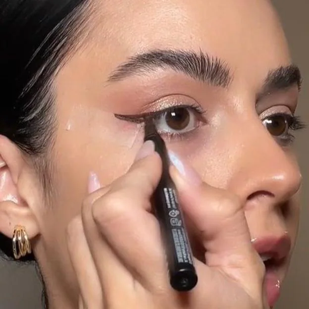 Influencer usando cinta adhesiva para delinear los ojos